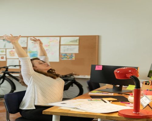 Woman stretching her arms while sitting at her office desk