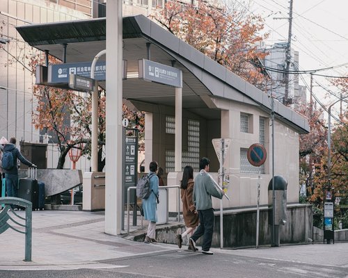 People walking towards a subway station entrance in a city