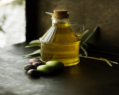 Variety of fresh vegetables and olive oil on a rustic kitchen table