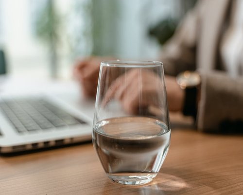Glass of water next to a laptop on a desk